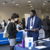 Recruiter in a blue suit talking to a student at a career fair.